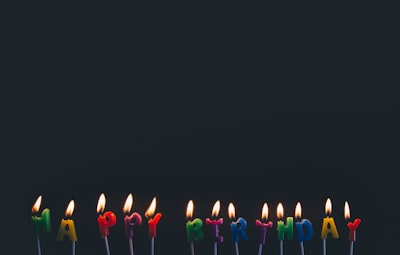 assorted-color happy birthday candles with flames happy birthday teams background