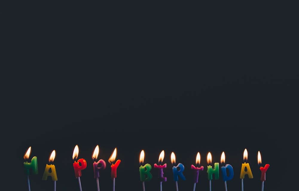 farblich sortierte Happy Birthday Kerzen mit Flammen