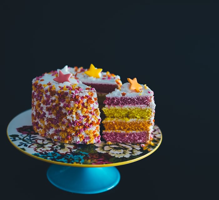 Colorful cake topped with stars, on a cake plate with flowery design.