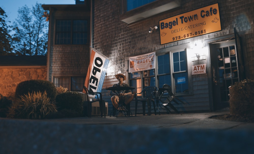 a person sitting at a table outside of a cafe