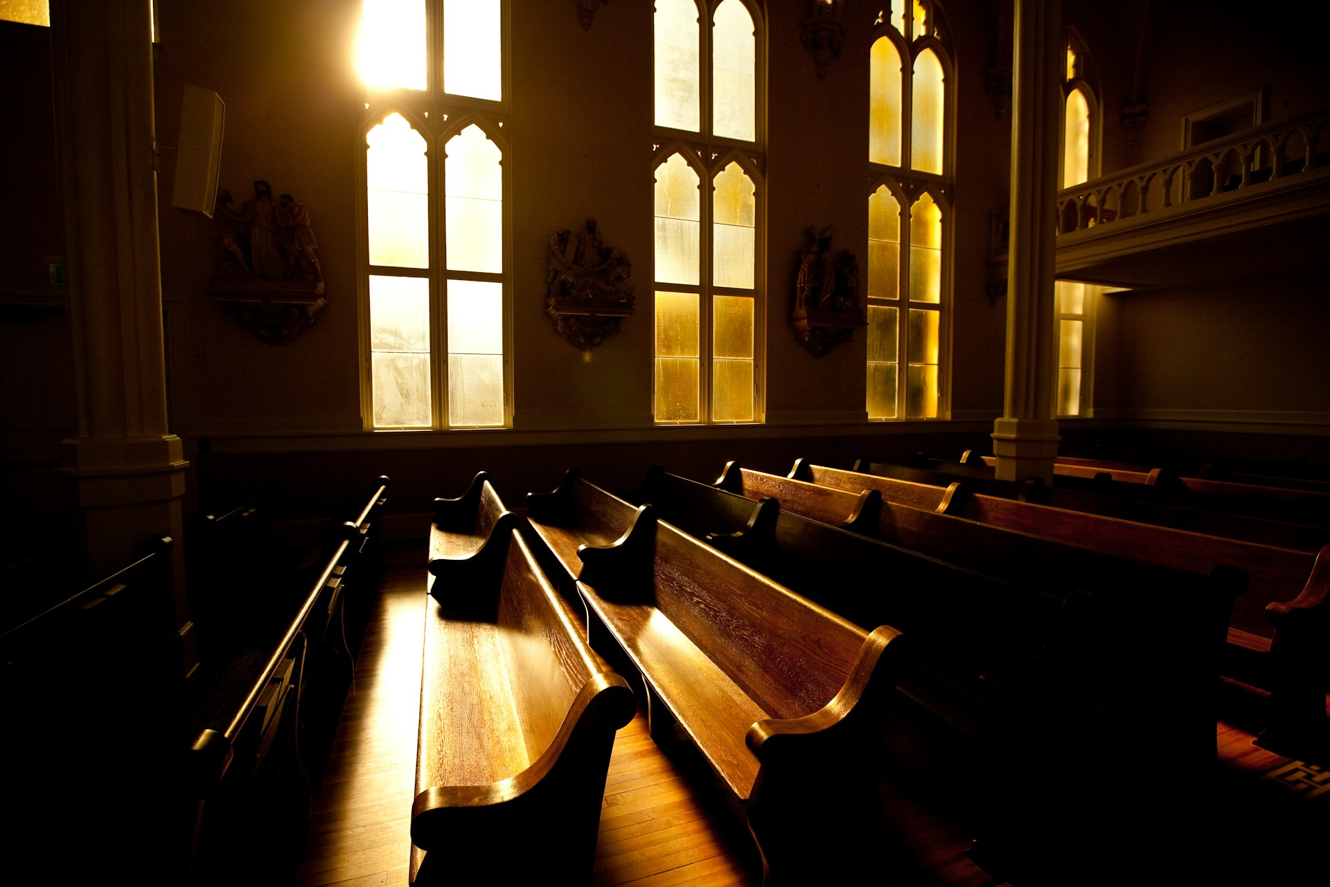 A warm and inviting interior of a church with sunlight streaming through stained glass windows.