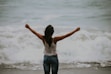 woman in white spaghetti strap top standing on the seashore