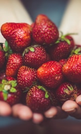 shallow focus photography of strawberries on person's palm