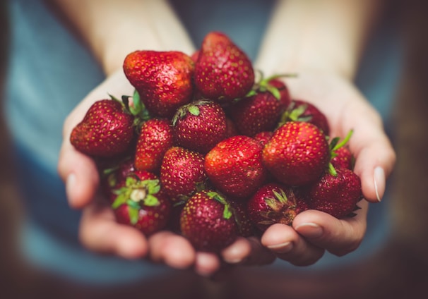 shallow focus photography of strawberries on person's palm