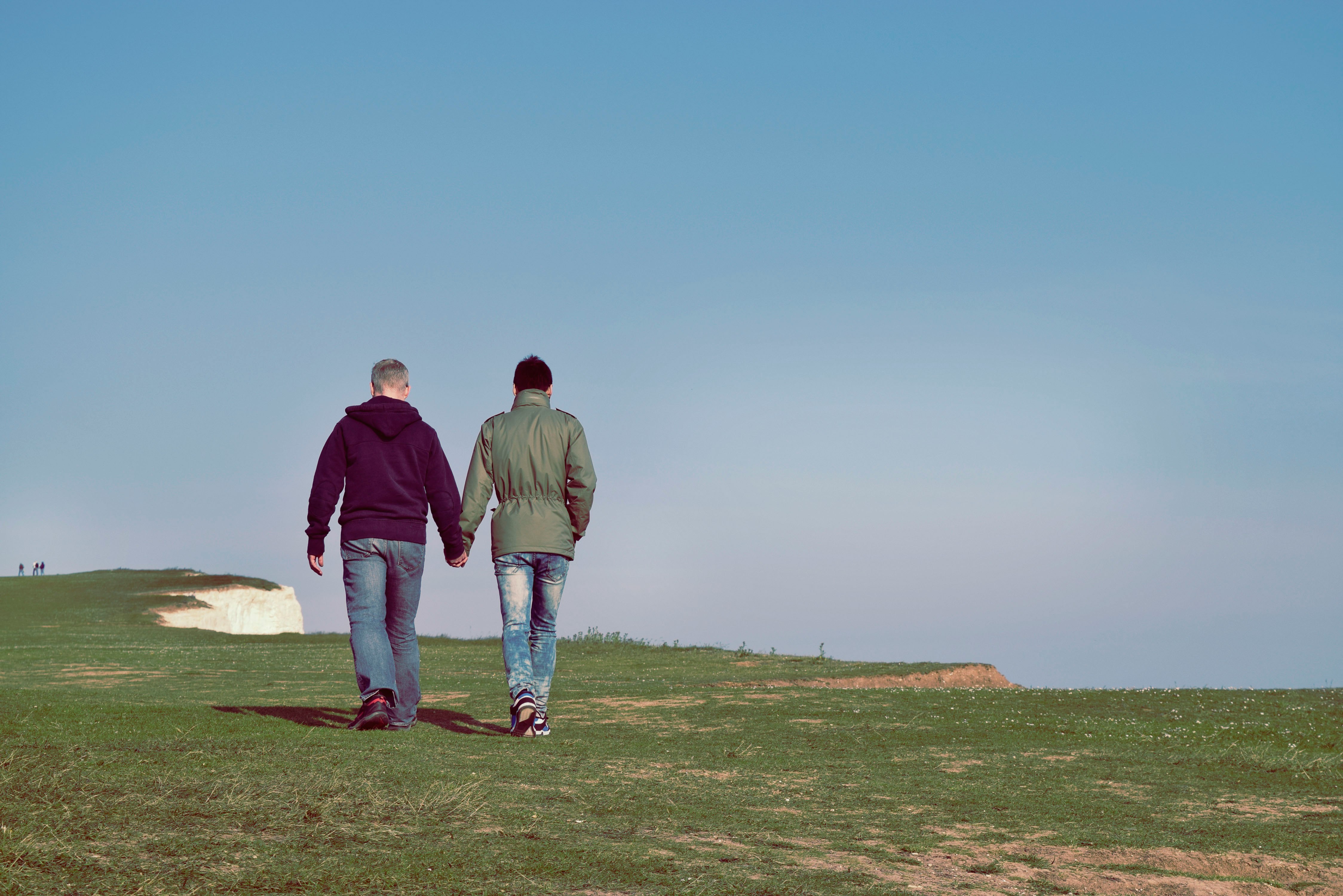 two person walking on green grass field