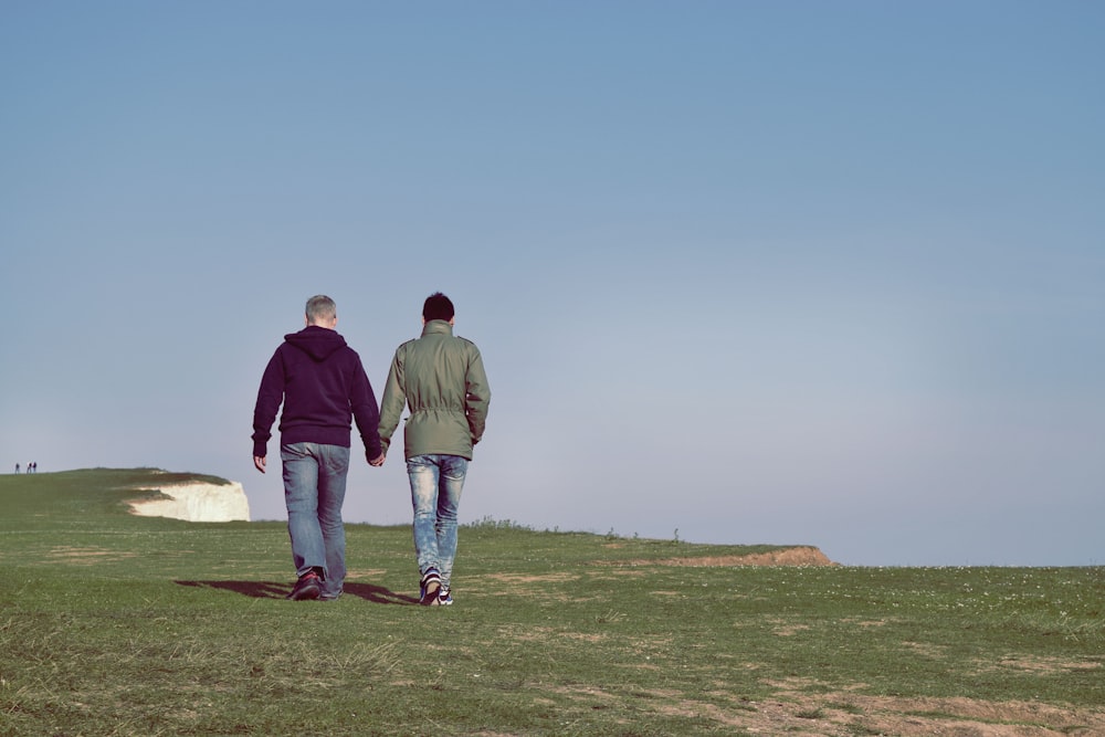 duas pessoas caminhando no campo de grama verde