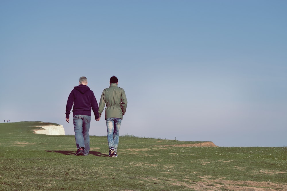 two person walking on green grass field
