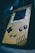 A retro handheld gaming device with a worn, yellowed exterior. The button layout includes a D-pad on the left and two circular buttons on the right, alongside 'Select' and 'Start' buttons. The screen appears slightly damaged with scratches and signs of age.