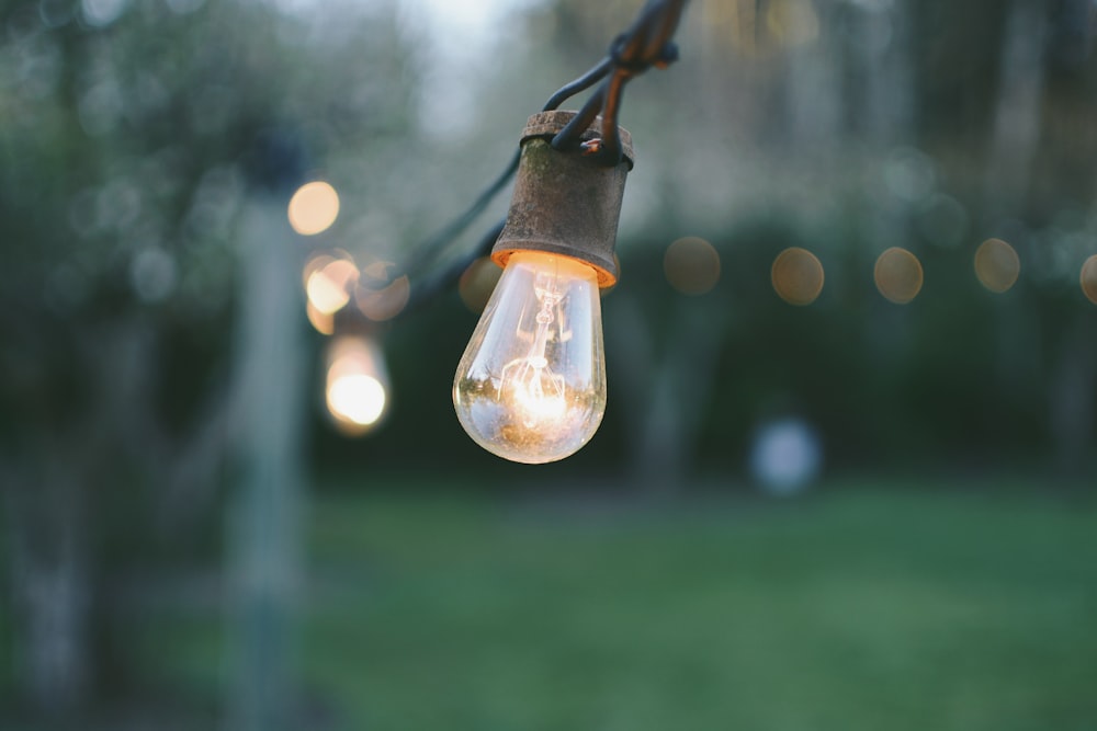 Close-up of a light bulb on a long horizontal wire outdoors