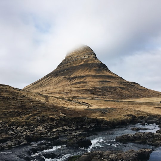 brown mountain covered by clouds in Kirkjufell Iceland