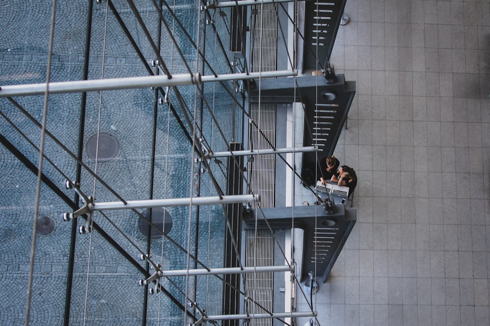 aerial photography of man and woman sitting near gray metal pillars