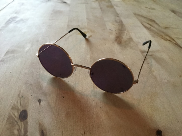 Close-up of elegant glasses frames displayed on a wooden table with natural sunlight.