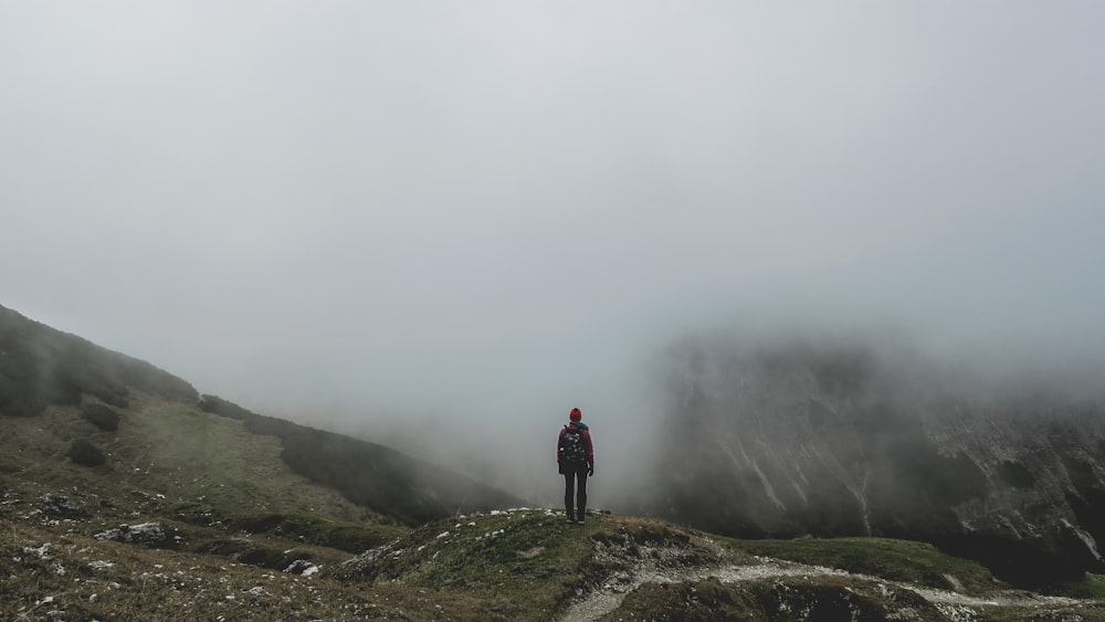 pessoa em pé na montanha verde perto da fumaça durante o dia