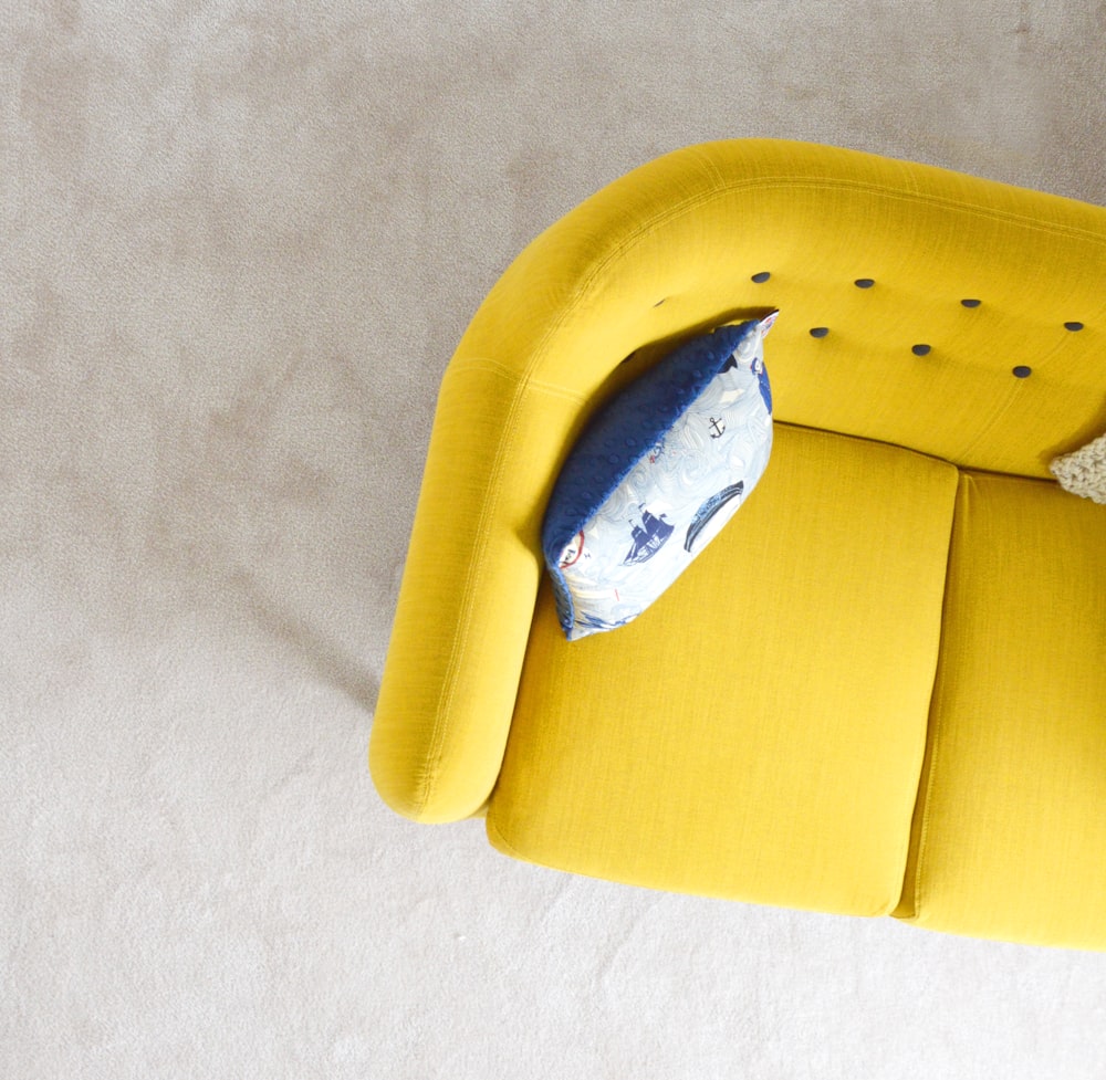 スロー枕付き黄色の布製ソファ