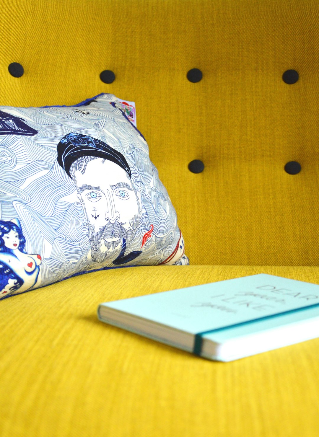 Yellow hipster sofa with captain Ahab on it and a book. 