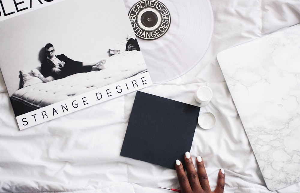 a person's hand on a bed next to a vinyl album