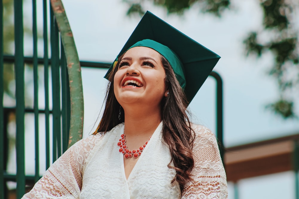 A woman wearing a graduation cap smiling and looking up at the sky