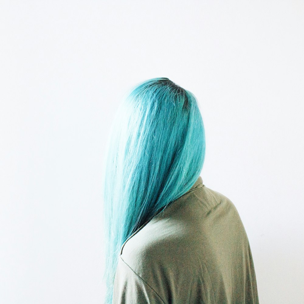 mujer de pelo verde azulado con top marrón