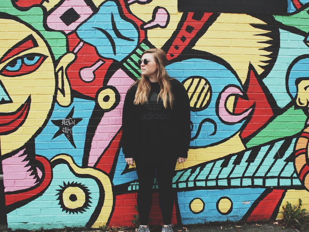 mulher em pé ao lado do muro com grafite