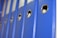 A row of blue office binders is aligned on a shelf, each featuring a circular metallic ring for easy handling. The focus is on the binders, with a perspective that captures their uniformity and professional appearance.