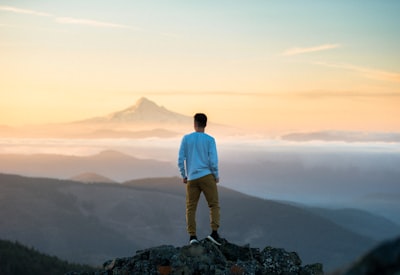 man standing on top of mountain brave teams background