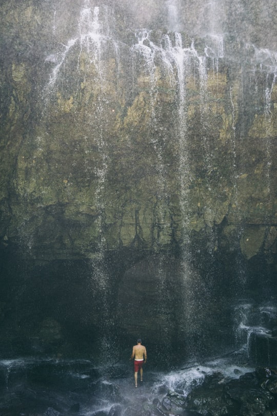 man standing underneath waterfall in Virgin Falls United States