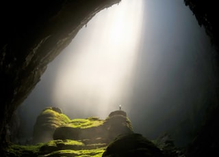 person on top of rock formation inside cave