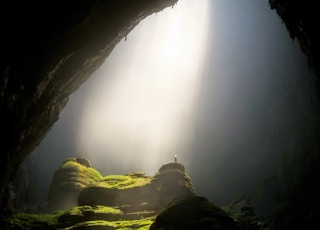 person on top of rock formation inside cave