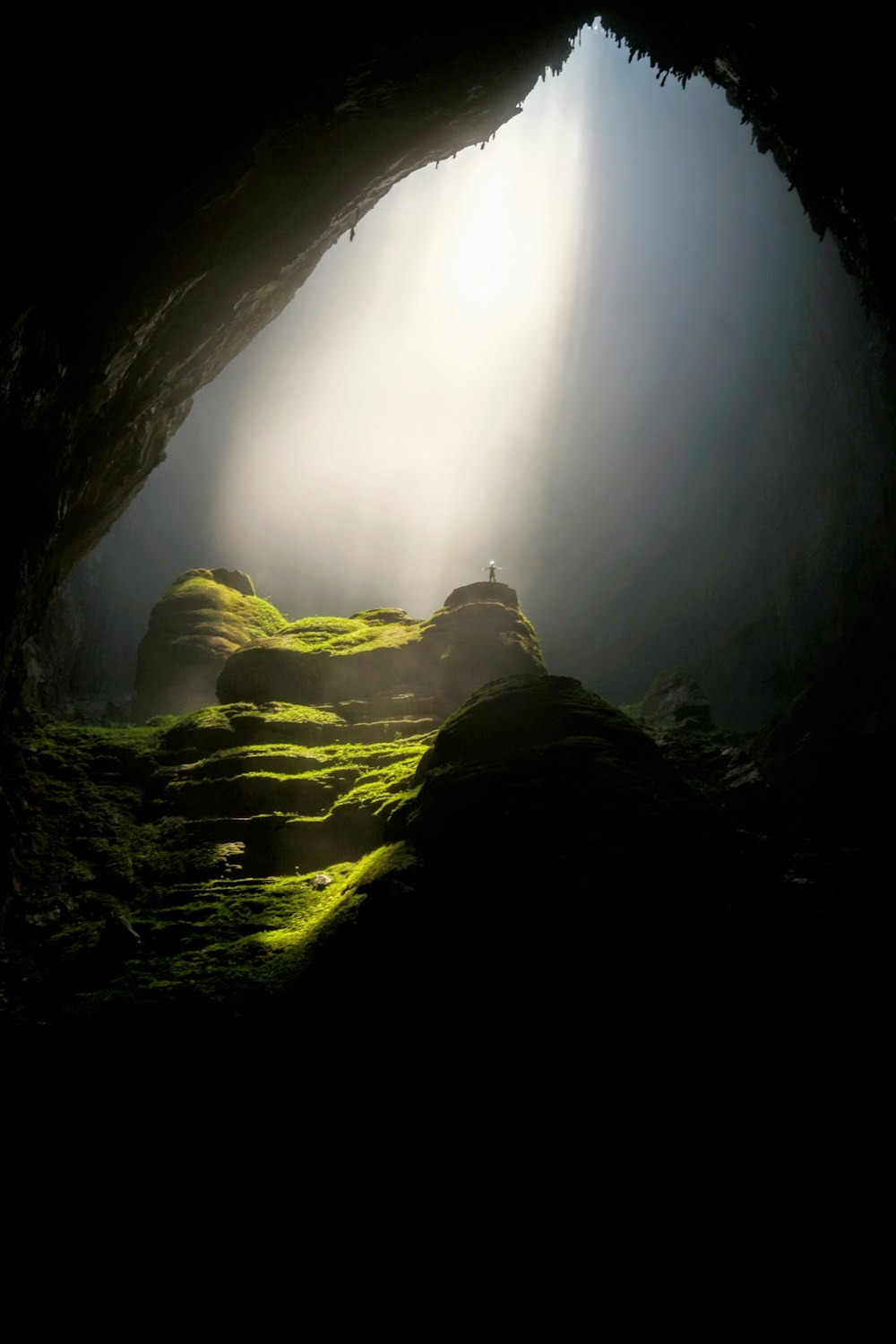 person on top of rock formation inside cave