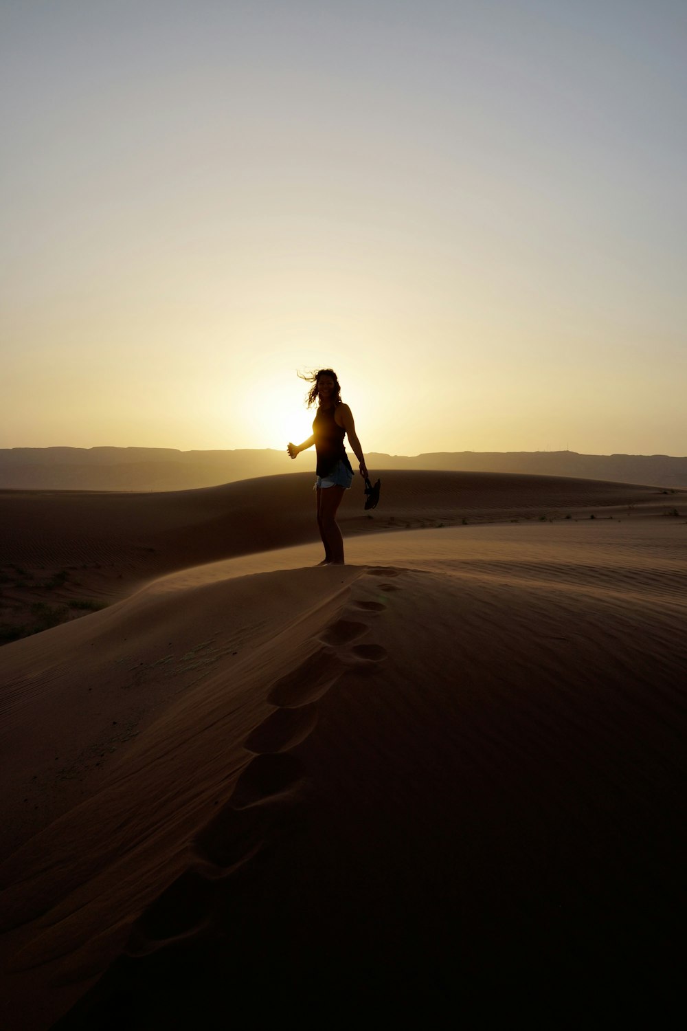 woman standing on sand during sunset