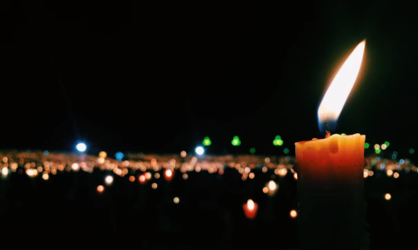 Close-up of a candle flame glowing warmly, symbolizing hope and remembrance.