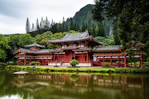 Japanese style temple near calm water behind mountain at daytime