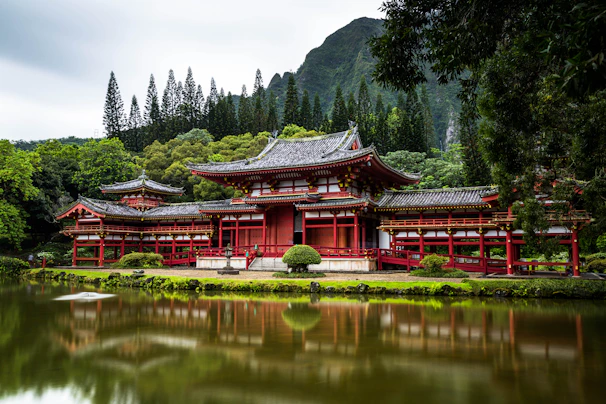 Japanese style temple near calm water behind mountain at daytime