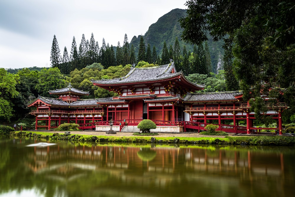 Tempel im japanischen Stil in der Nähe von ruhigem Wasser hinter Bergen am Tag