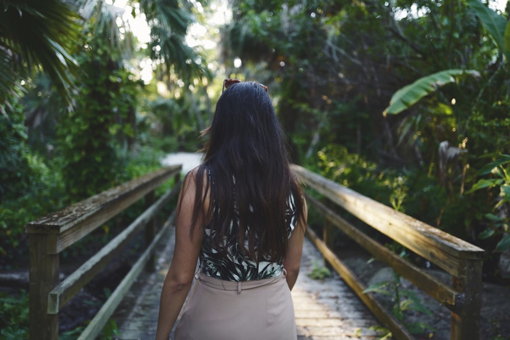 woman wearing black sleeveless top walking on dock