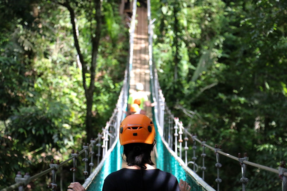 woman crossing hanging bridge during day