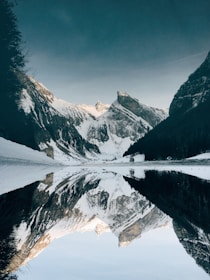 snow-covered mountain near lake under blue sky
