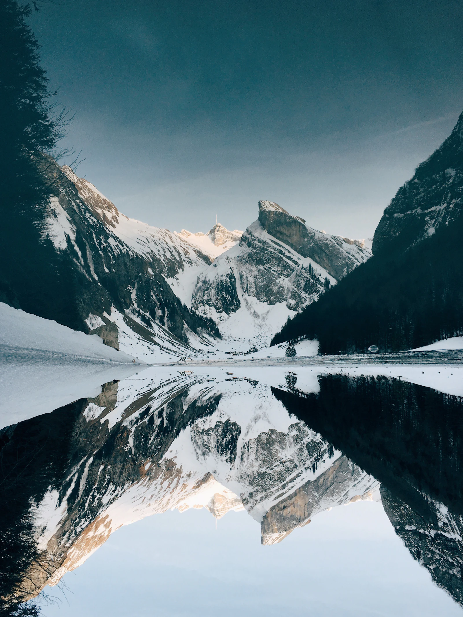 Montagnes enneigées se reflétant dans un lac calme, invitation au voyage lent