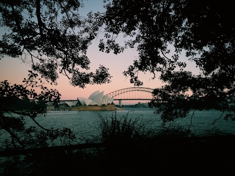 Australian flag with Sydney Opera House and Harbour Bridge at dawn.