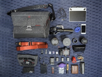 A pastel-themed flat lay of various action cameras with travel accessories on a soft background.