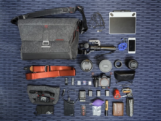 A pastel-themed flat lay of various action cameras with travel accessories on a soft background.