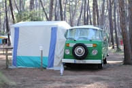 The camper van parked under towering pine trees with golf bags strapped on the back.