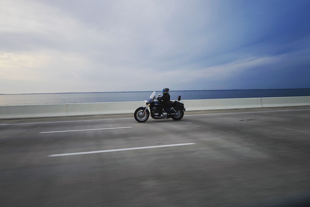 personne conduisant une moto de tourisme sur une route en béton gris