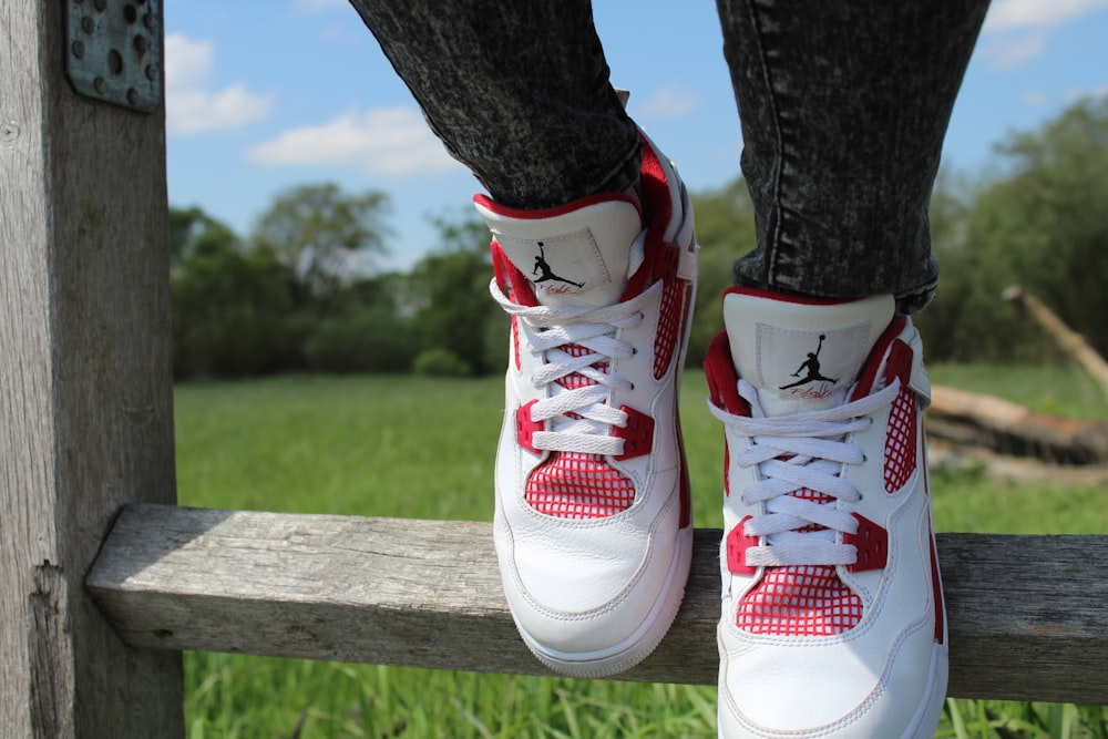 pessoa usando par de sapatos Air Jordan vermelhos e brancos