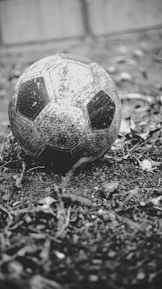 Close-up of a worn football on a cobblestone street, symbolizing travel and sport.