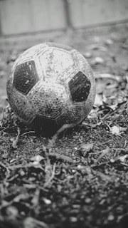A worn-out football resting on the grass near the stands, symbolizing the heart of the game.