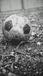 A vintage football with a worn leather surface resting on a grassy field, symbolizing the history of the sport.
