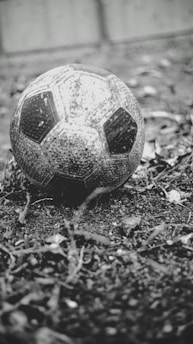 A vintage football with a worn leather surface resting on a grassy field, symbolizing the history of the sport.