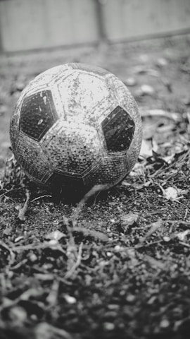 Close-up of a worn football on a cobblestone street, symbolizing travel and sport.