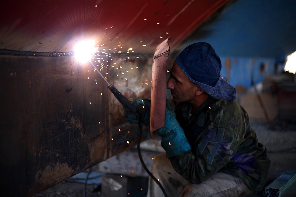 man welding the brown metal board